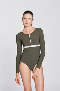 Front view of a woman wearing a hunter green swimsuit with long sleeves, white button strip and white line under the bust, in front of a white background.