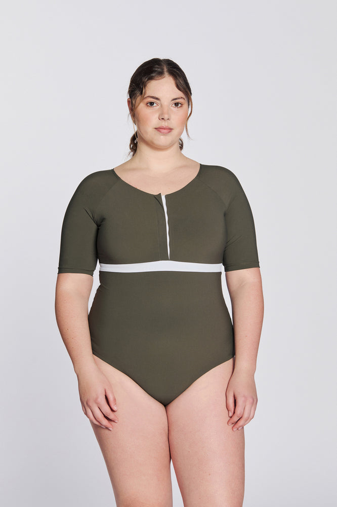 
                  
                    Front view of a woman wearing a hunter green swimsuit with short sleeves, white button strip and white line under the bust, in front of a white background.
                  
                