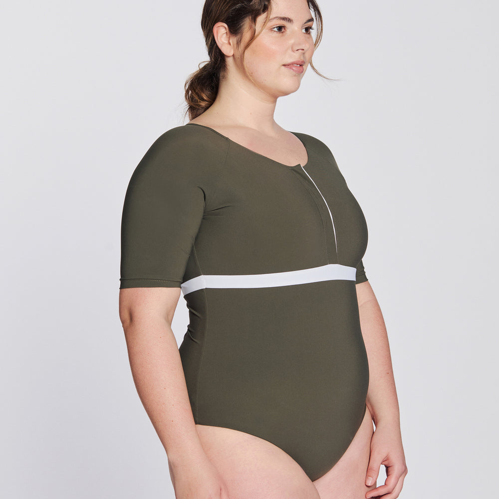 
                  
                    Side view of a woman wearing a hunter green swimsuit with short sleeves, white button strip and white line under the bust, in front of a white background.
                  
                