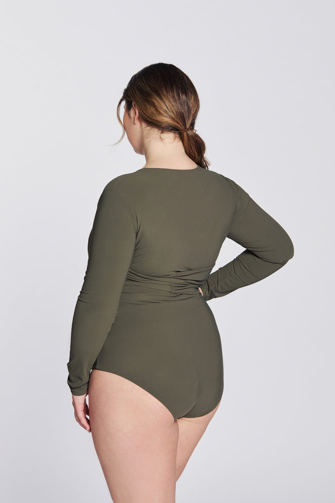 
                  
                    Back view of a woman wearing a hunter green swimsuit with long sleeves and wrap closing, in front of a white background.
                  
                