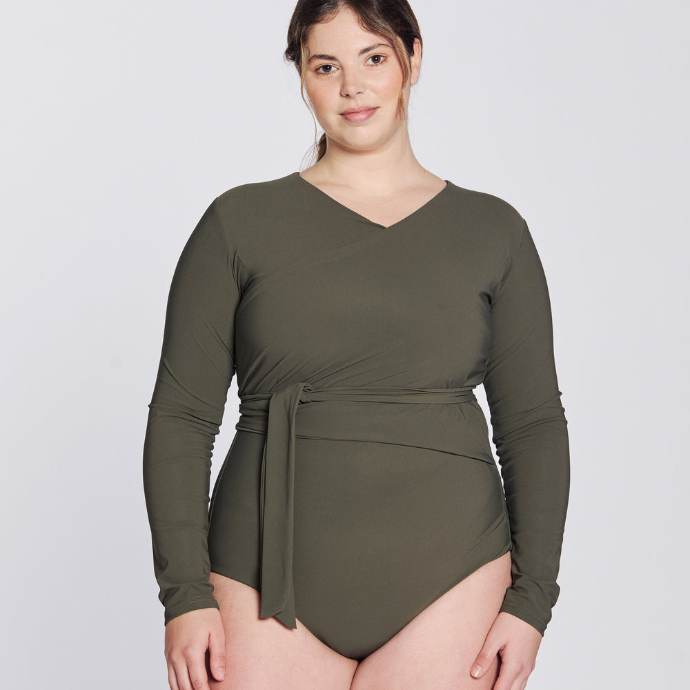 
                  
                    Front view of a woman wearing a hunter green swimsuit with long sleeves and wrap closing, in front of a white background.
                  
                