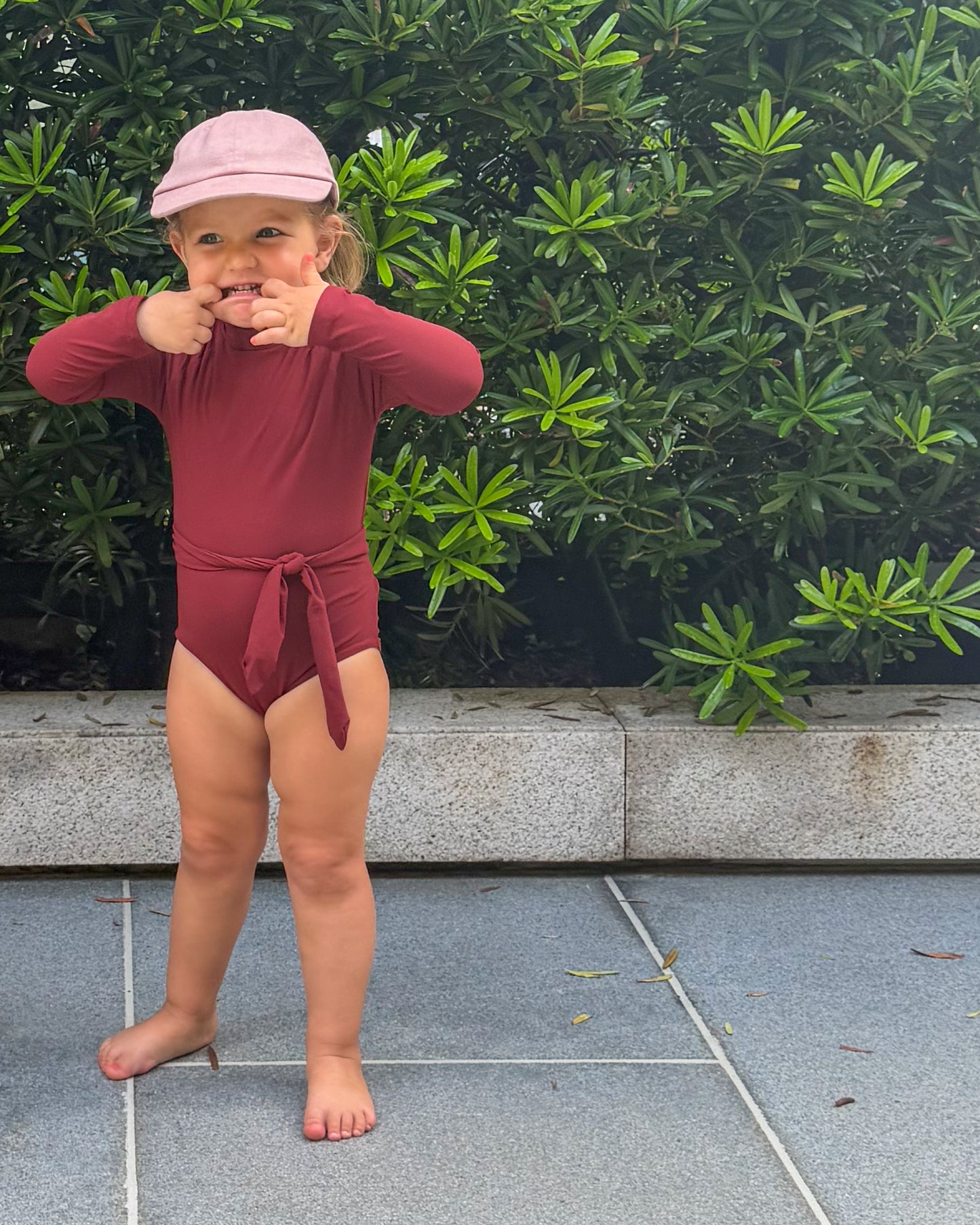 Child in a red swimsuit with long sleeves and high neckline.
