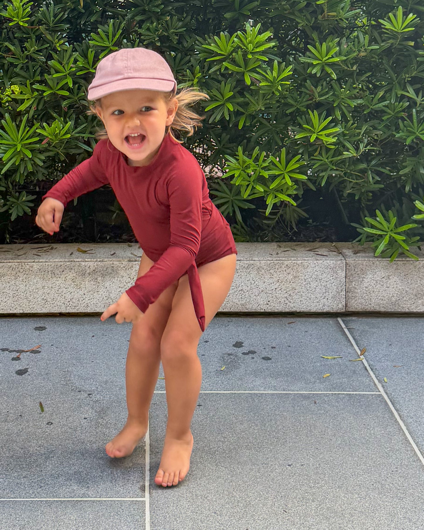 child in a red swimsuit with long sleeves jumping around.